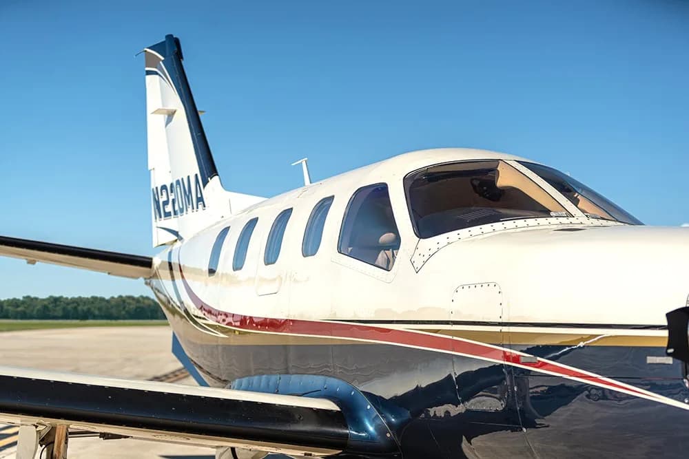 A close-up view of the tail and cockpit area of the white, blue, and gold painted turboprop aircraft (N220MA).