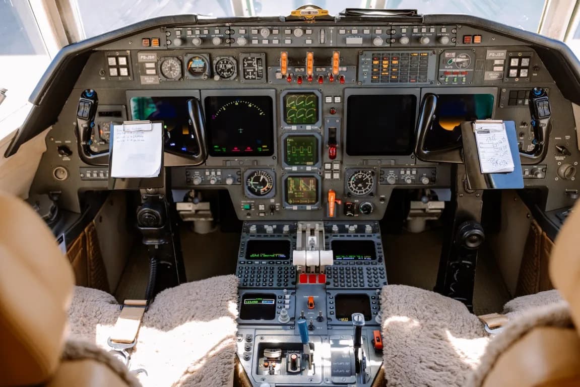 The detailed cockpit of a business jet, featuring multiple display screens, instruments, and control panels.
