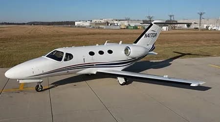 A white business jet with blue and black stripes, tail number N417GR, parked on an airport tarmac.