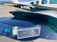 A close-up of the nose of a Beechcraft Bonanza with a white and green paint scheme.