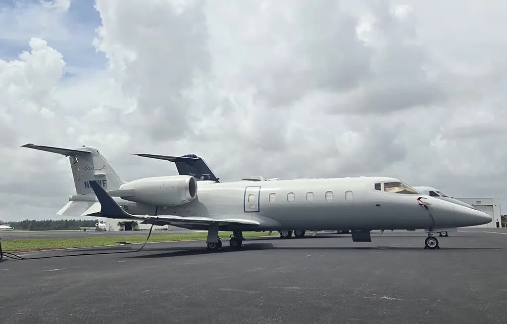 A Learjet business jet, registration N61WF, in a light gray paint scheme, parked on an asphalt tarmac.