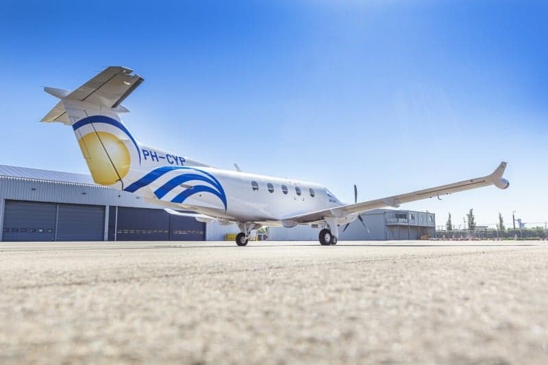 A Pilatus PC-12 aircraft with registration PH-CYP parked on the tarmac in front of a hangar.