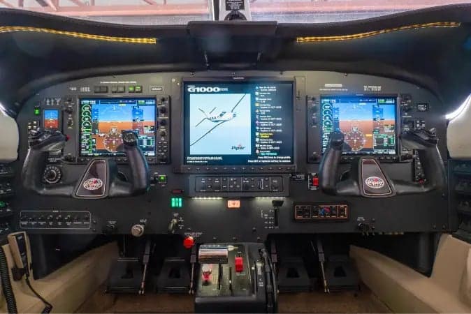 The cockpit of a Piper M-class aircraft, featuring a Garmin G1000 NXi avionics suite with multiple display screens and control yokes.