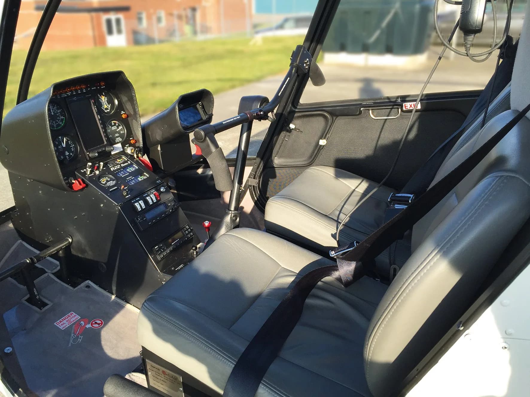 The grey interior and cockpit of a Robinson R22 Beta II helicopter are shown from the passenger side.
