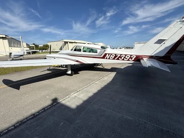 Side view of a white twin-engine aircraft with N87393 on the tail, parked on an airfield.