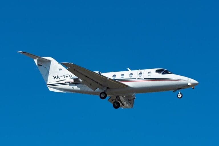 A white jet with gold stripes parked on the tarmac.