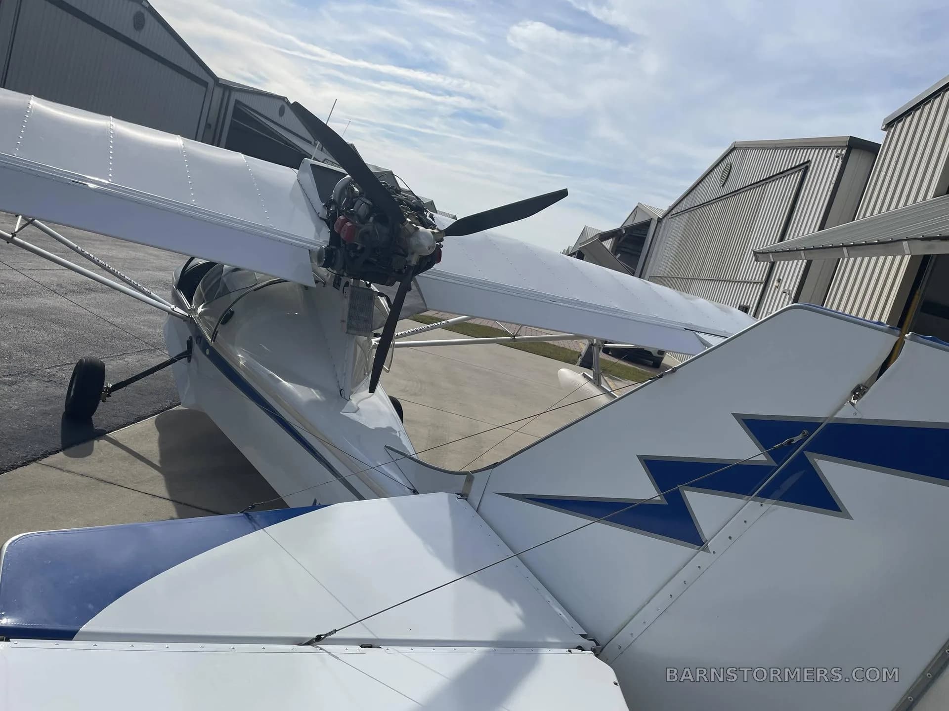 A rear-quarter view of a white and blue Searey amphibious aircraft (N1080) with its engine and propeller visible.