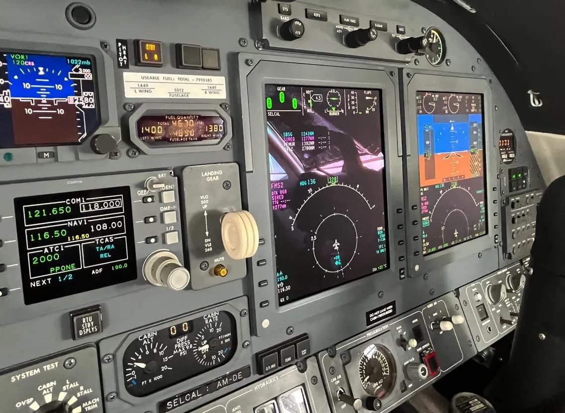 A close-up view of a business jet's instrument panel, showing various digital displays and controls.