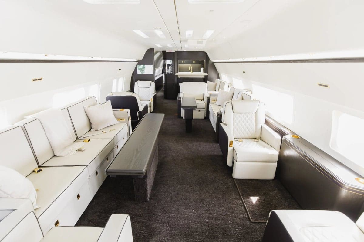 Wide view of the aircraft's interior with white leather seating and dark wood accents.
