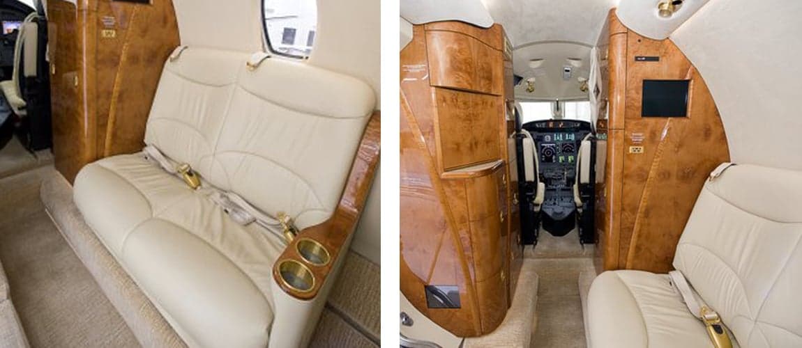 Interior of the aircraft featuring cream-colored leather seats and wood paneling.