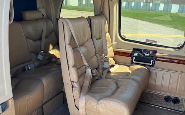 The interior of the helicopter with tan leather seats and wood trim.