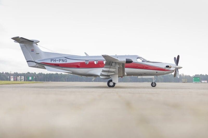 A Pilatus PC-12 aircraft with a silver and red paint scheme, registration PH-PNG, parked on the tarmac.
