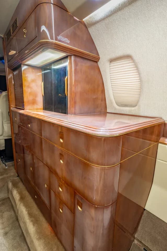A close-up view of the polished wood cabinetry and a window in the aircraft's interior.