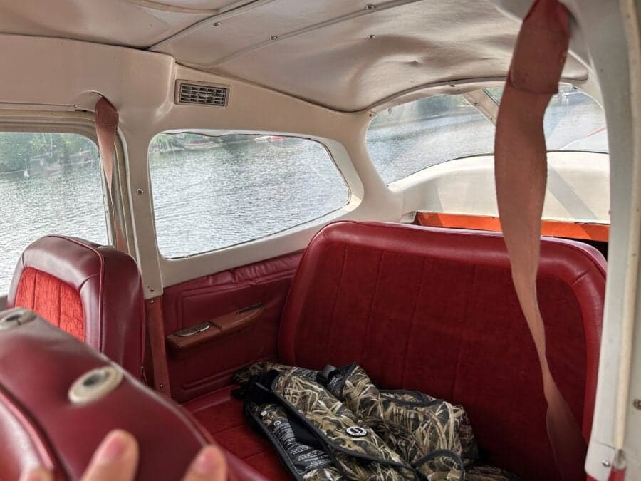 The interior of the Cessna floatplane features red seats and a view of the rear window.