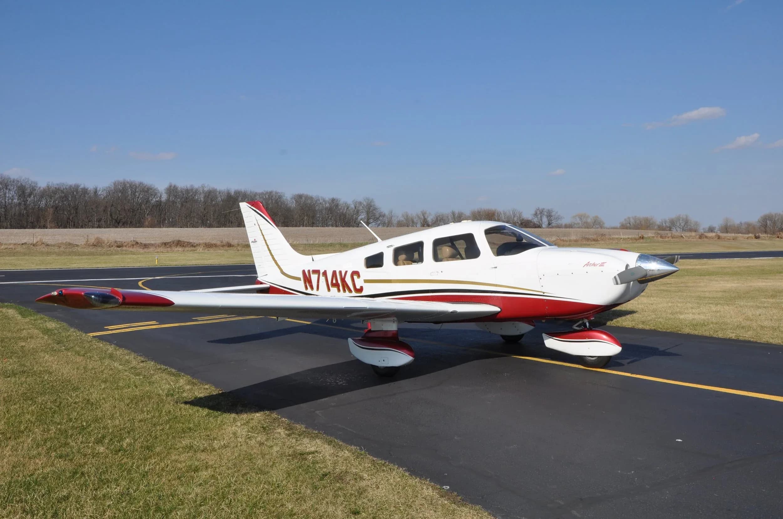 Piper Archer III aircraft with a white and red paint scheme on the tarmac.
