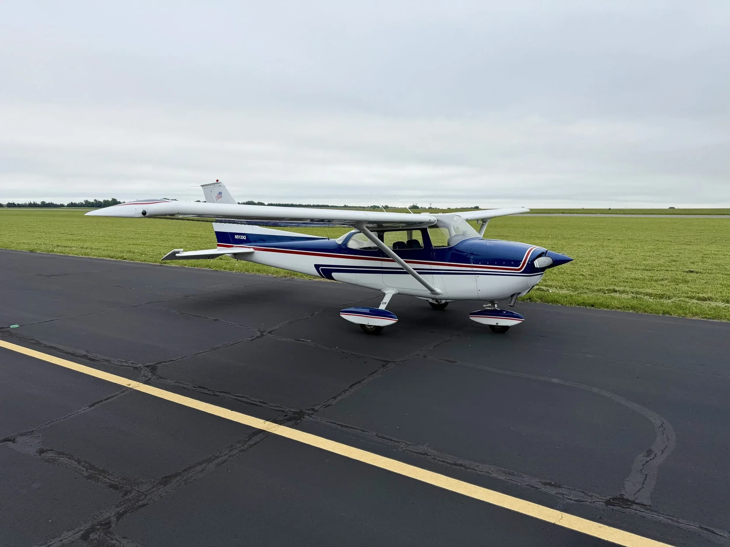A blue and white Cessna 172 aircraft with registration N5133Q parked on an asphalt tarmac.