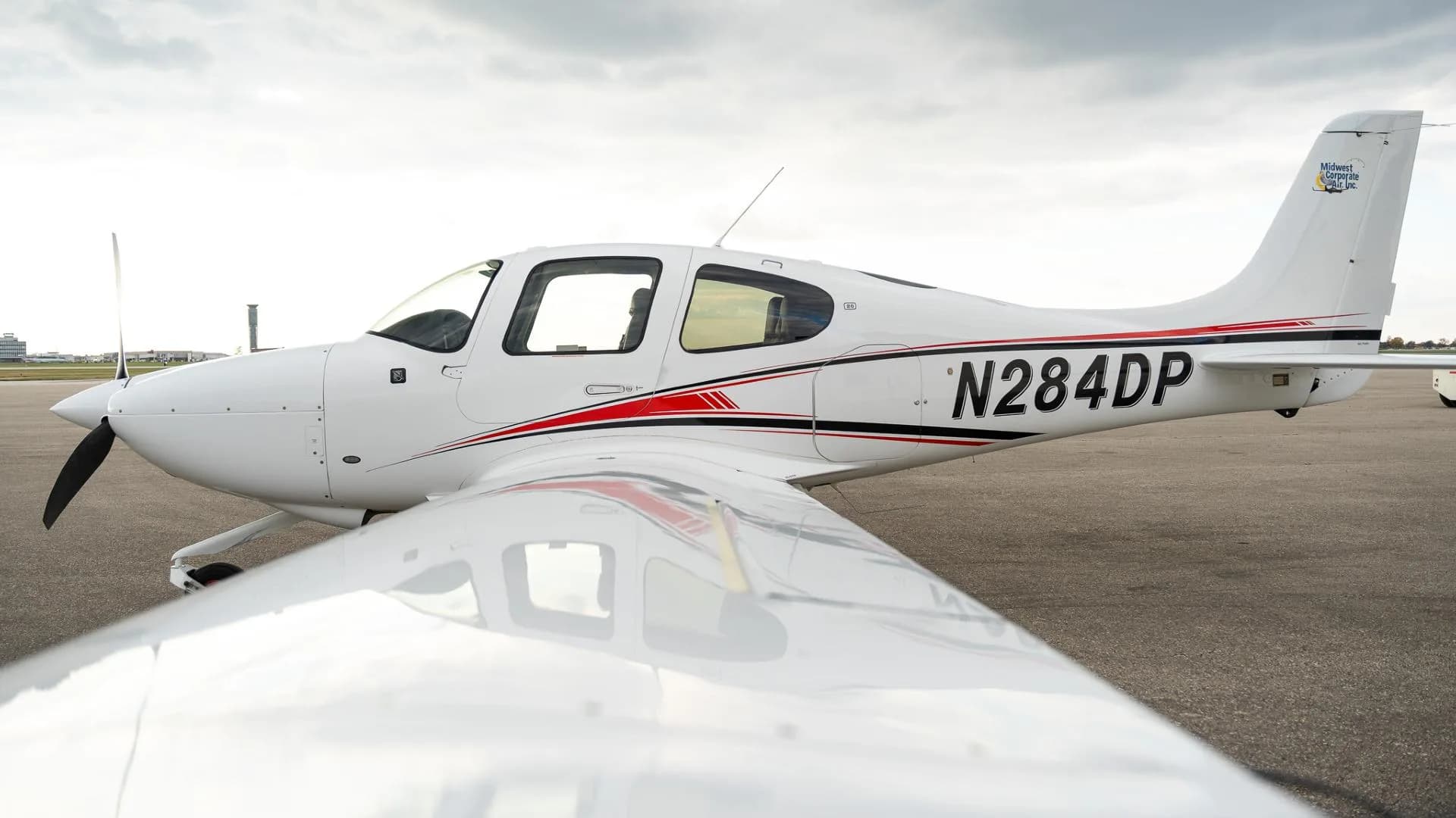 A close-up side view of the white Cirrus SR22 aircraft showing the N284DP registration and red and black stripes.