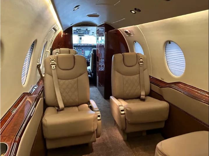 Aircraft cabin with tan leather seats and view towards the cockpit.
