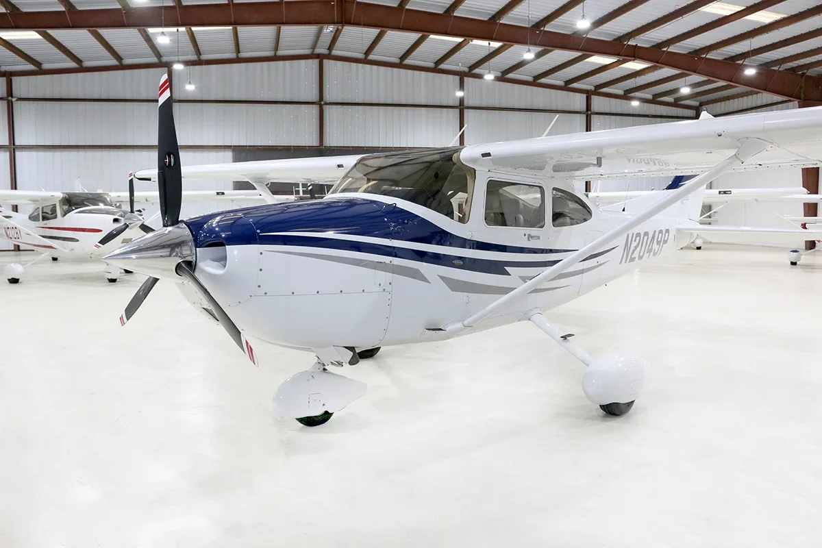 Front-right view of a white and blue Cessna Skylane TC (N2049P) parked in a hangar.