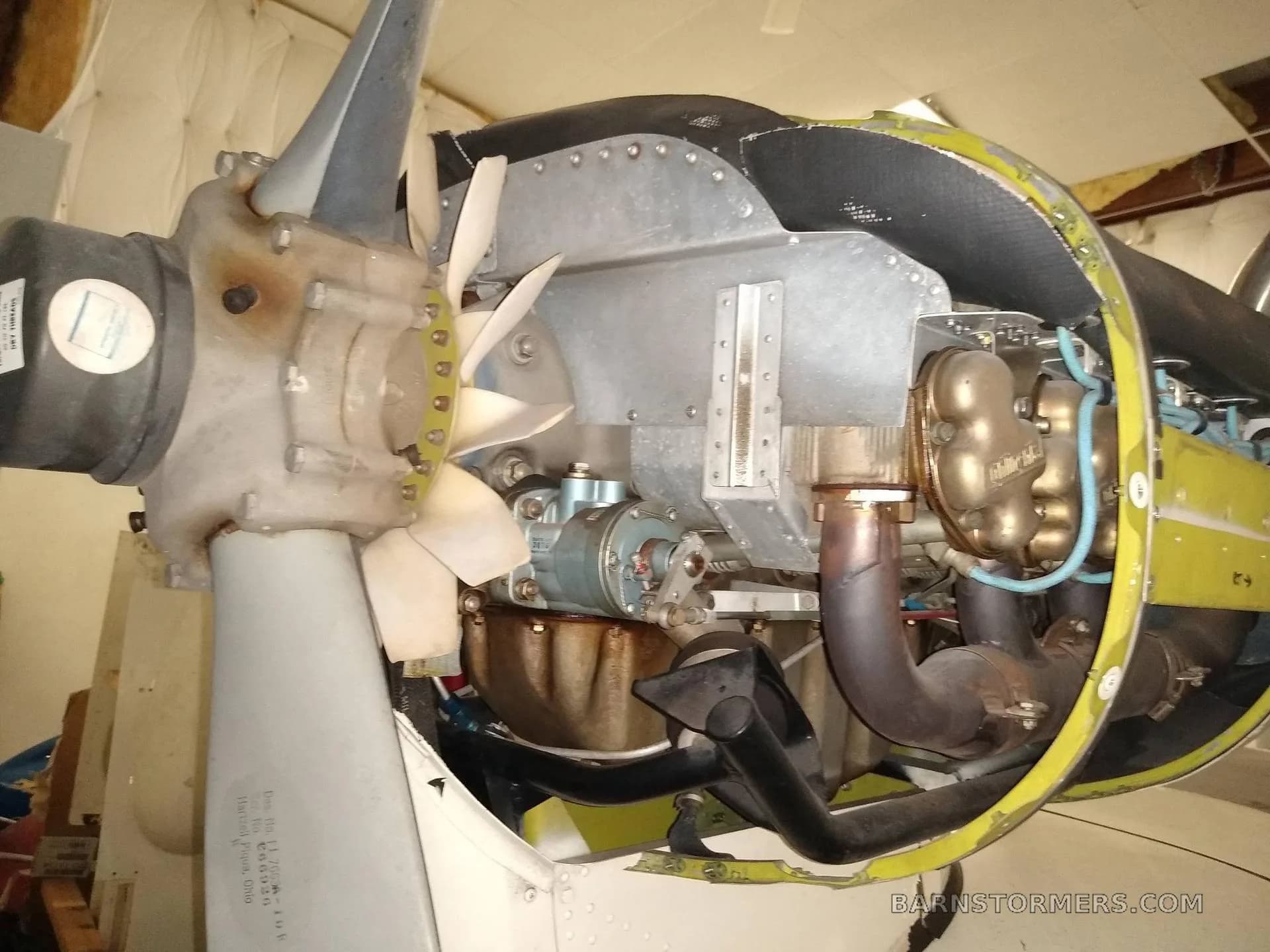 A close-up view of an aircraft engine and propeller with the cowling removed, revealing internal components.