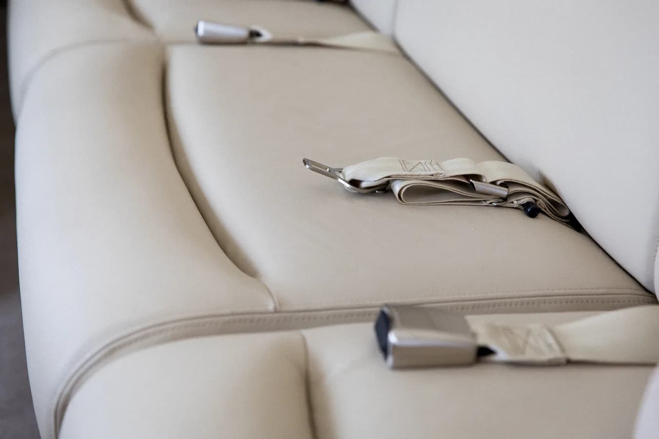 Close-up of the aircraft interior showing the leather seats and seatbelts.