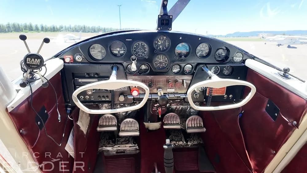 The cockpit of a 1950 Cessna 170A, featuring a black instrument panel with various gauges and two white control yokes.