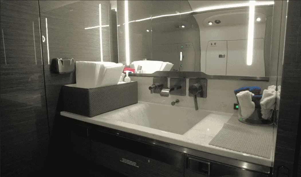 The lavatory of a business jet featuring a modern sink, mirror, and amenities.