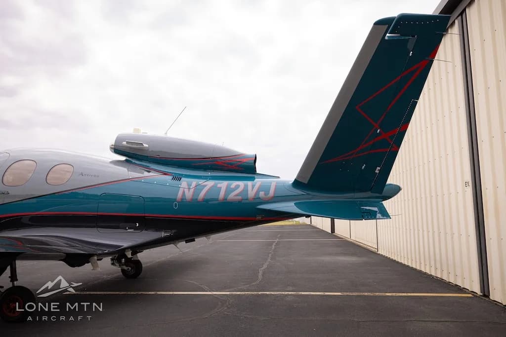 A close-up view of the teal V-tail of the Cirrus Vision Jet (N712VJ) with red accents.