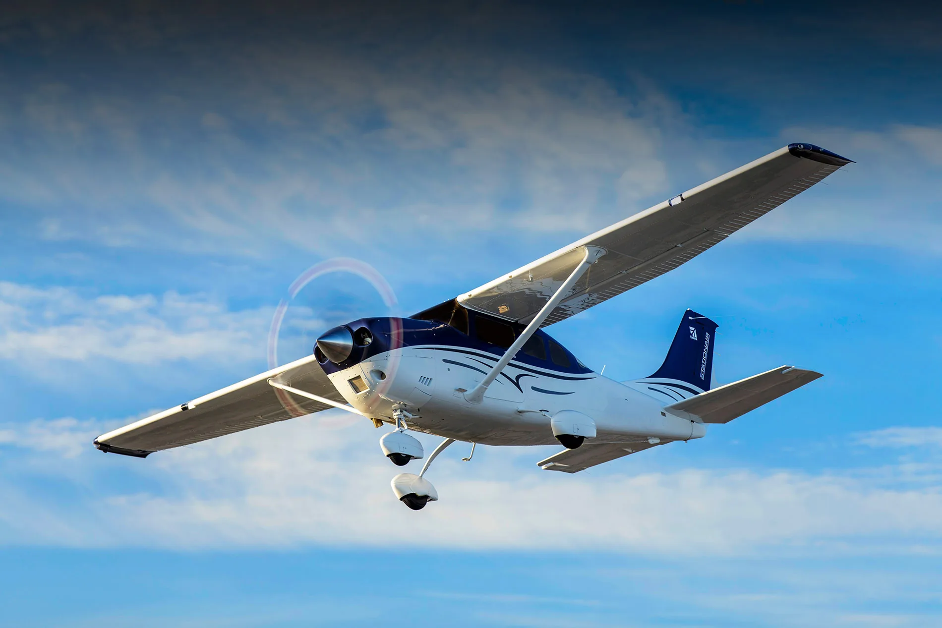 A Cessna Stationair in flight against a blue sky.
