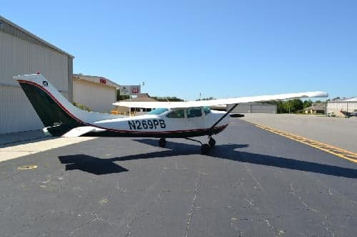 Cessna 206H Stationair with registration N269PB parked on the tarmac near a hangar.