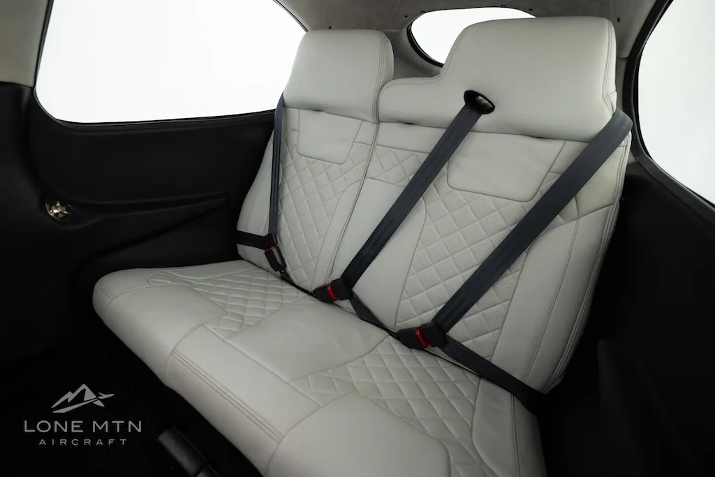 The light gray quilted leather rear seats of a Cirrus SR22 aircraft cabin with seatbelts.