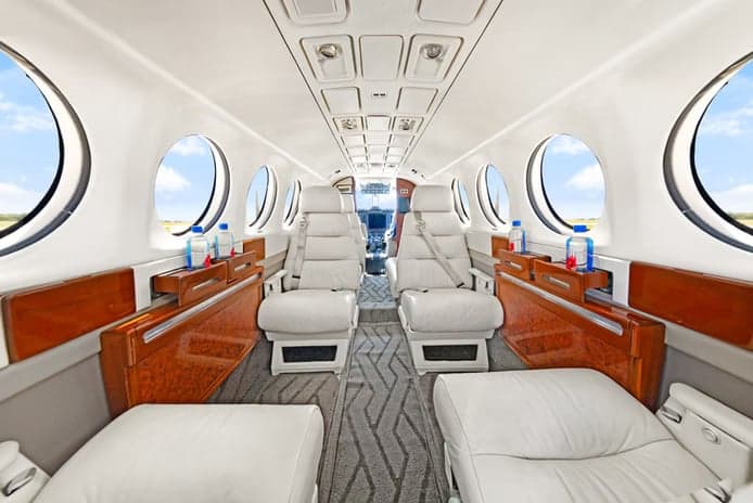 The interior cabin of a Beechcraft King Air 200 with white leather seats.
