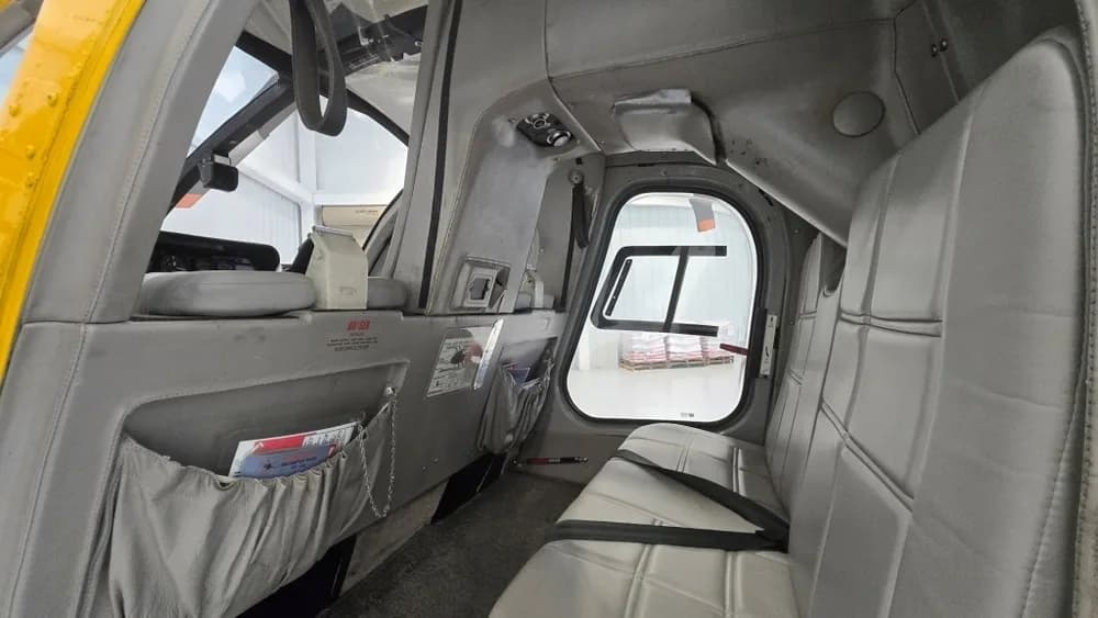 A wider view of the helicopter's grey interior cabin with rear seating and magazine pockets.