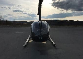 Front view of a black Robinson helicopter on the tarmac.