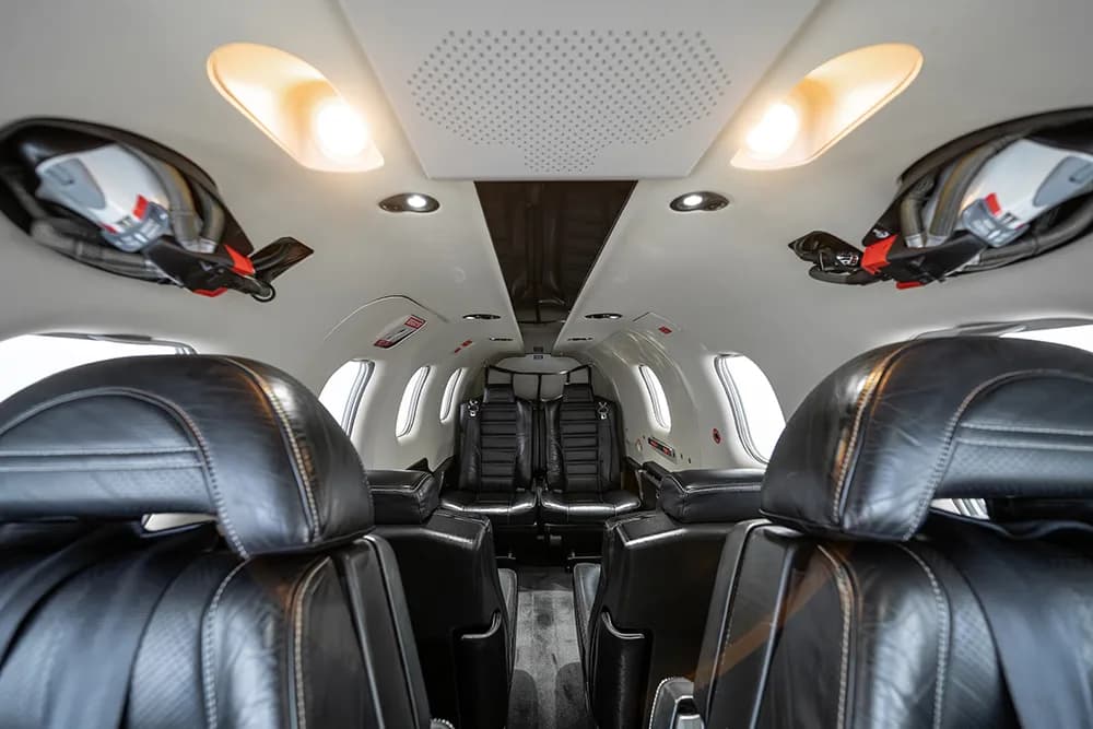 Interior view of the aircraft cabin looking towards the rear, showing overhead panels and lighting.