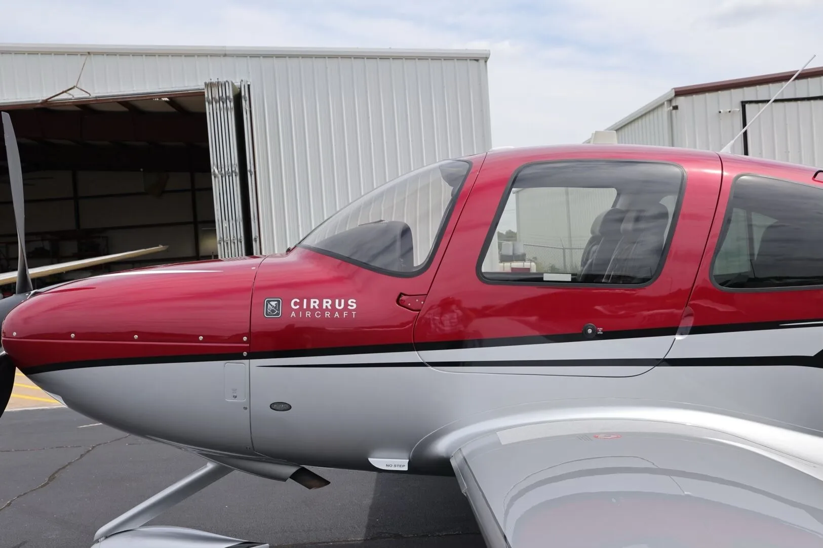 A close-up view of the nose and cockpit area of the red and silver Cirrus SR22T aircraft.