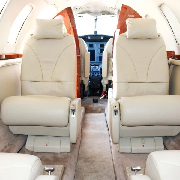 View from the cabin looking forward into the cockpit, showing light beige leather seats.
