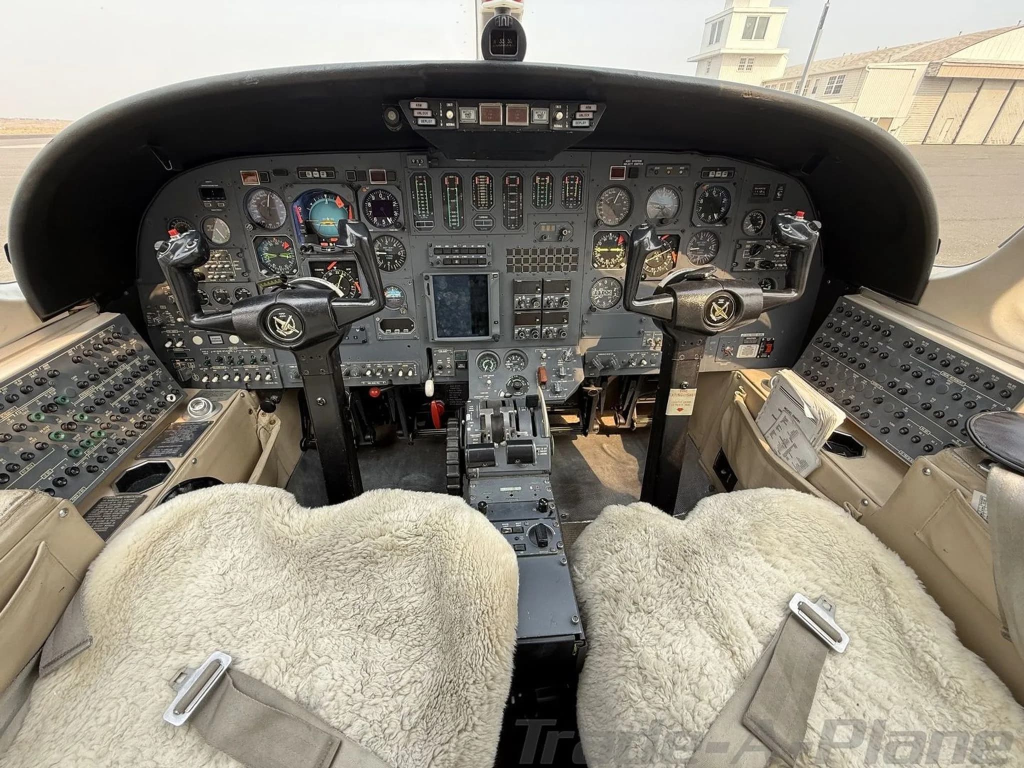 The cockpit of the Cessna Citation jet, N90JJ, showing the instrument panel, controls, and sheepskin seat covers.