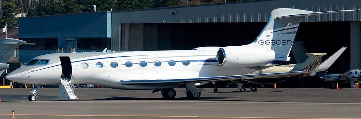 A white and silver Gulfstream G650ER parked on the tarmac with the boarding stairs down.