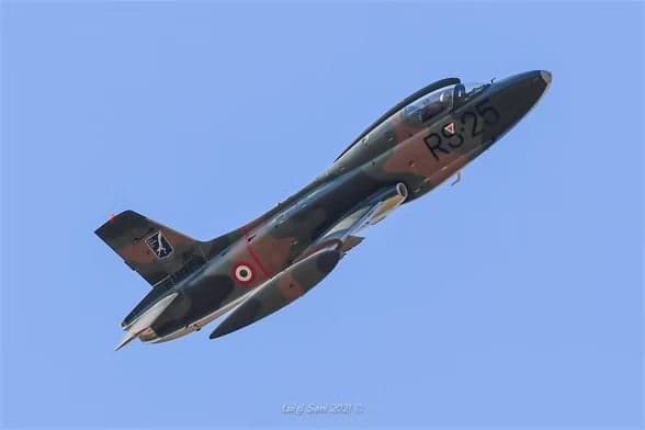 Camouflaged aircraft I-MBCK in flight against a blue sky.