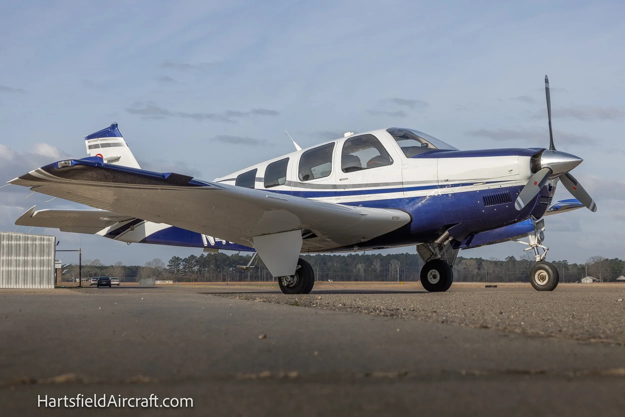 A Beechcraft Bonanza G36 aircraft on the ground, painted in white and blue.