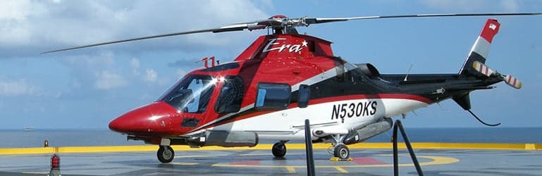 A red and white Era AgustaWestland AW139 helicopter on an offshore platform.