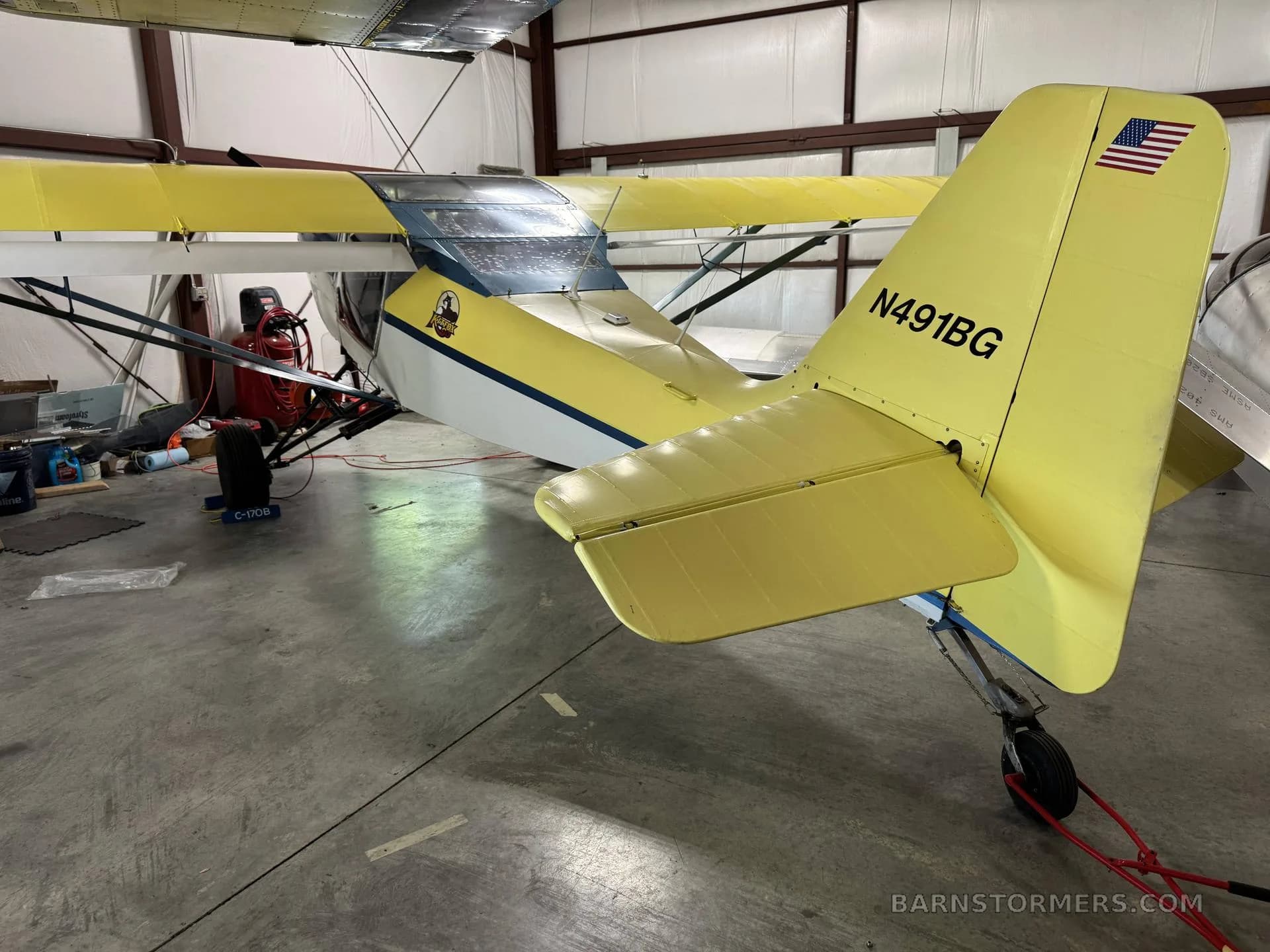 Rear view of a yellow Kitfox aircraft with registration N491BG, parked in a hangar.