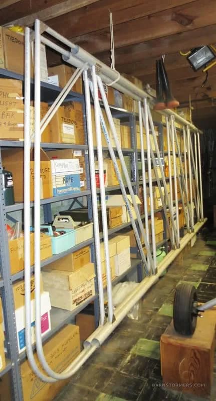 A long, tubular aircraft component, possibly a wing spar, stored vertically against shelves in a workshop.