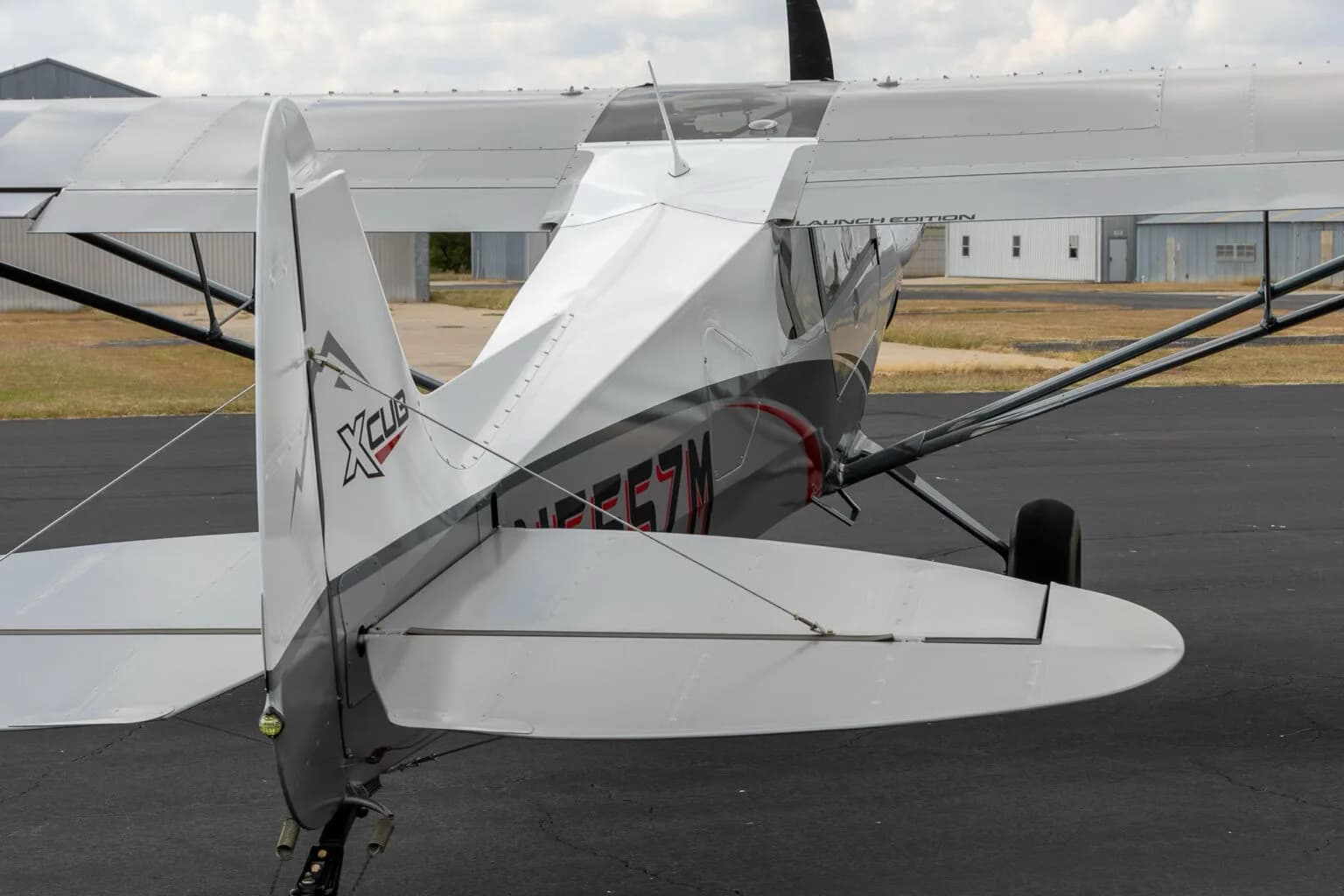 A close-up three-quarter rear view of the tail section of the white and grey X-Cub aircraft N555ZM.