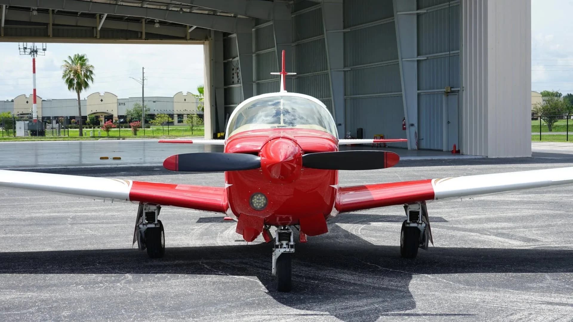 A head-on view of the red and white single-engine aircraft, N33YZ, showing its propeller and front landing gear.