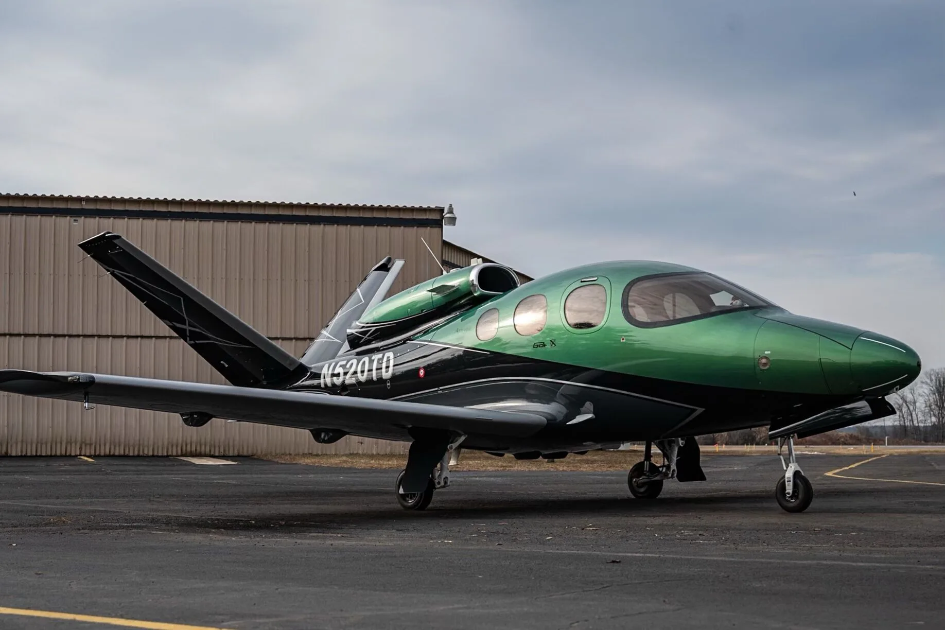 A three-quarter front view of the Cirrus Vision Jet N520TD in green and black paint scheme.