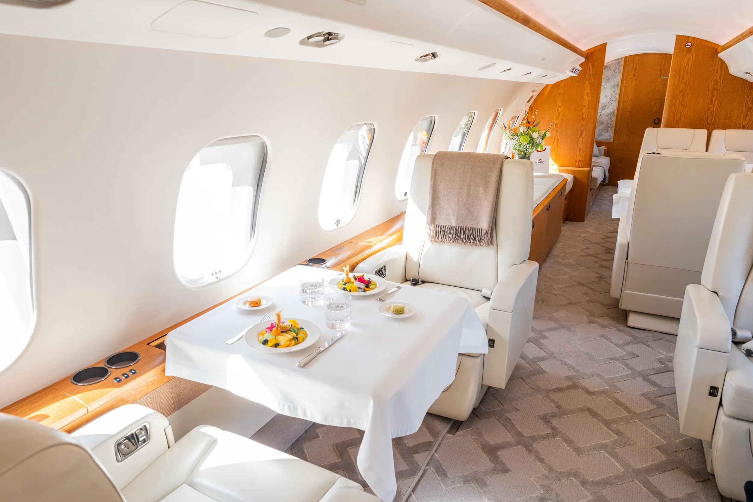 A dining table set with fruit plates and drinks inside a luxurious private jet cabin.
