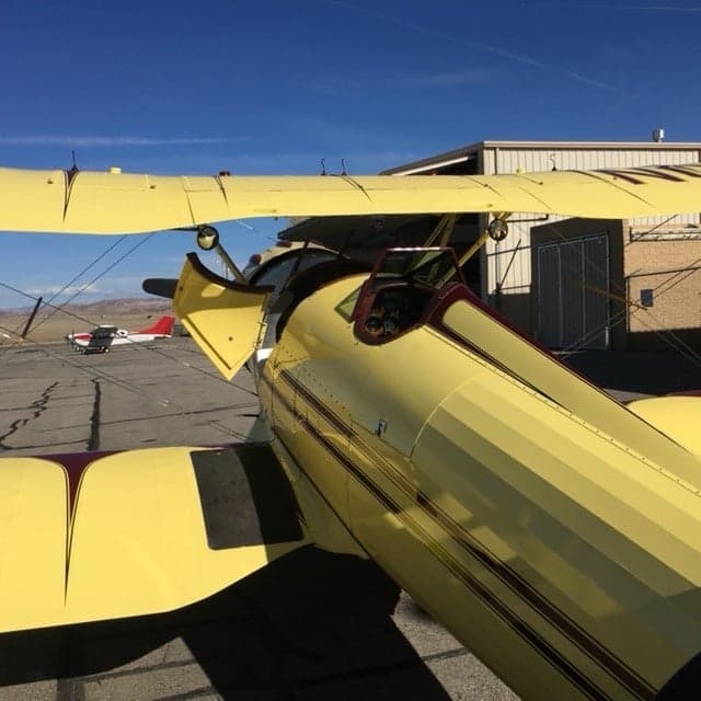 Front view of a yellow biplane with red accents.