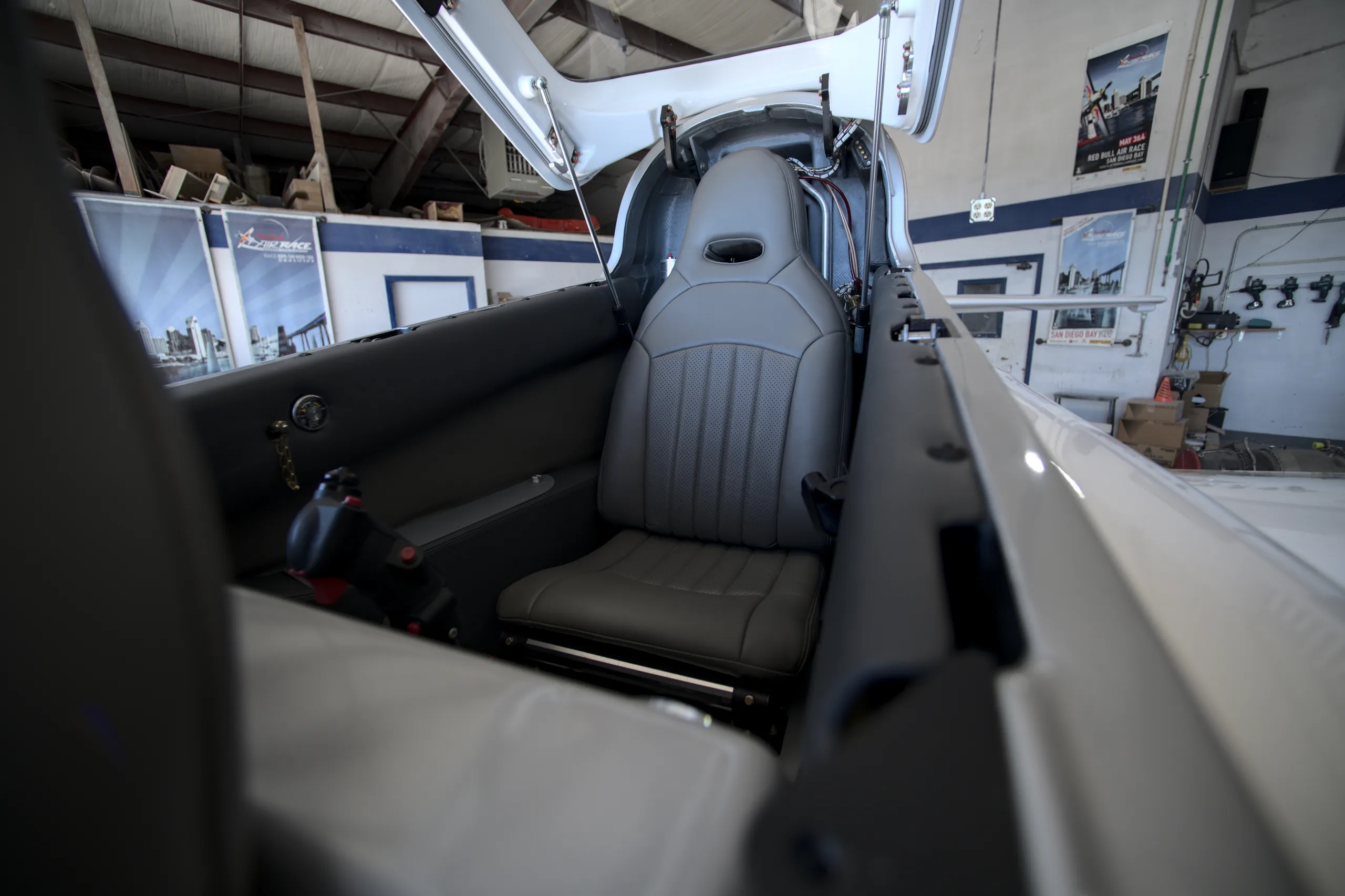 The gray leather seats and interior of a Viperjet aircraft, viewed from the rear looking forward in a hangar.